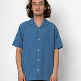 Man wearing a blue short-sleeve shirt against a white background