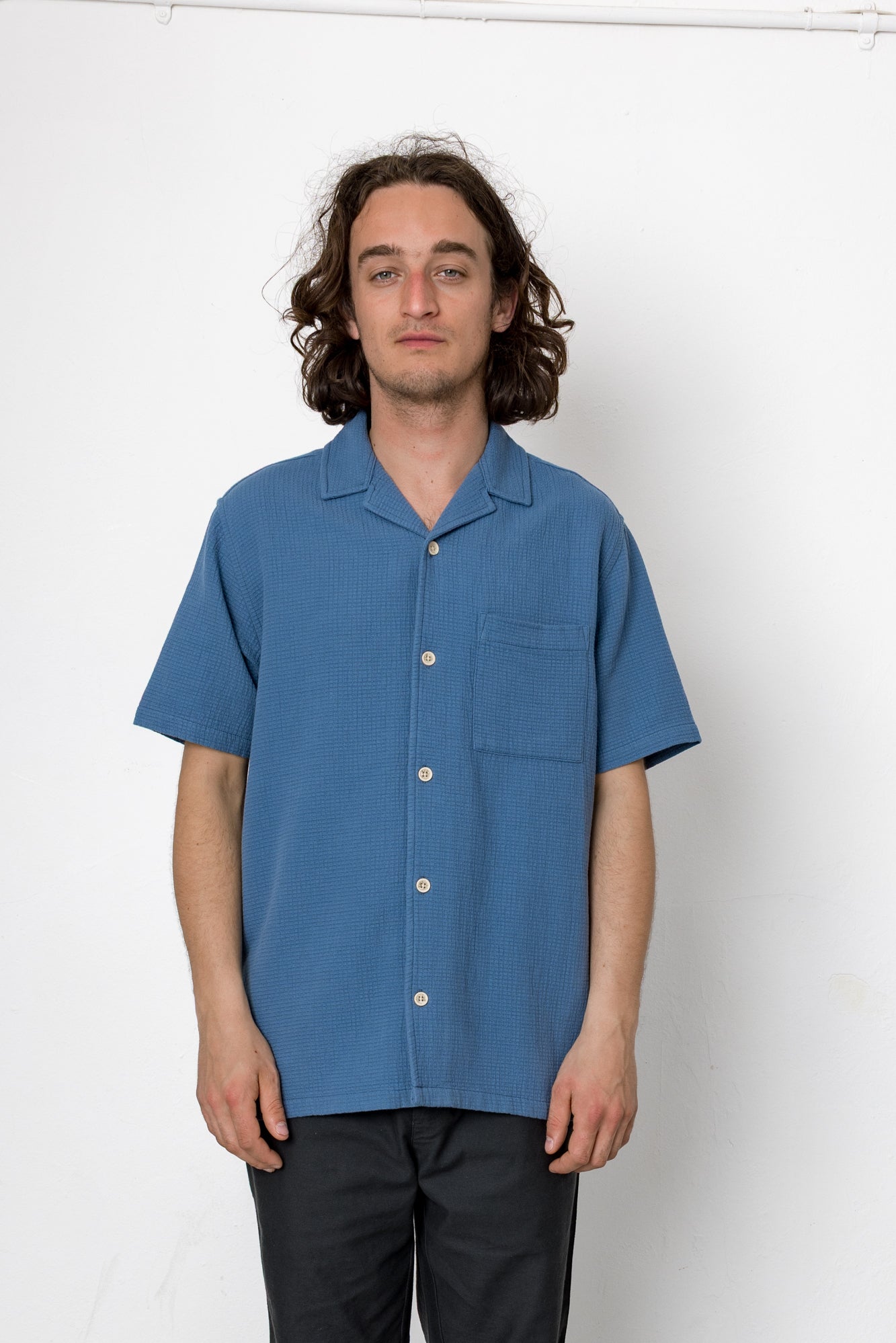 Man wearing a blue short-sleeve shirt against a white background