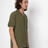 Man wearing a green shirt standing against a white background