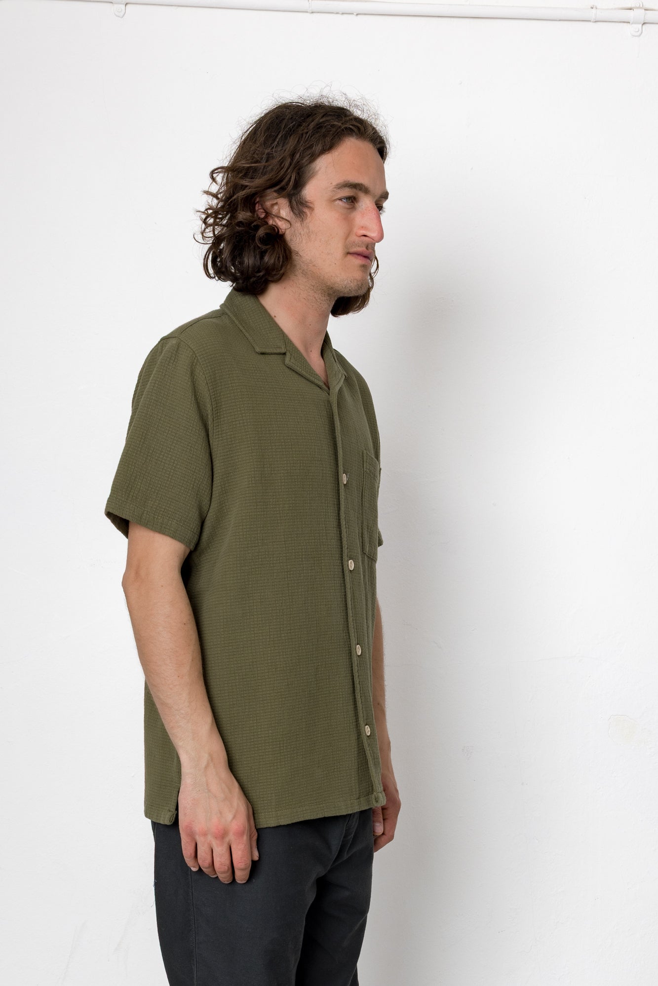 Man wearing a green shirt standing against a white background