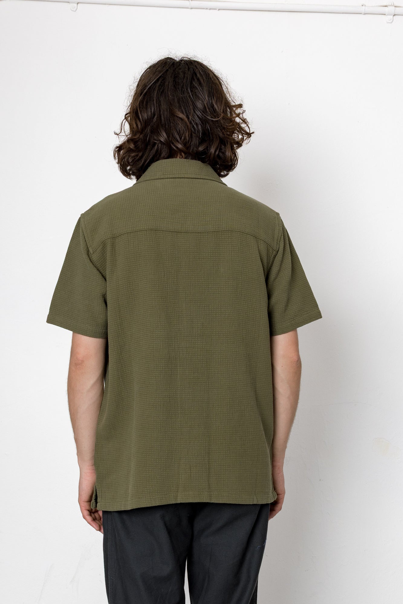 Person wearing an olive green shirt against a white background