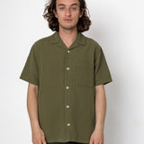 Man wearing an olive green short-sleeve shirt against a white background