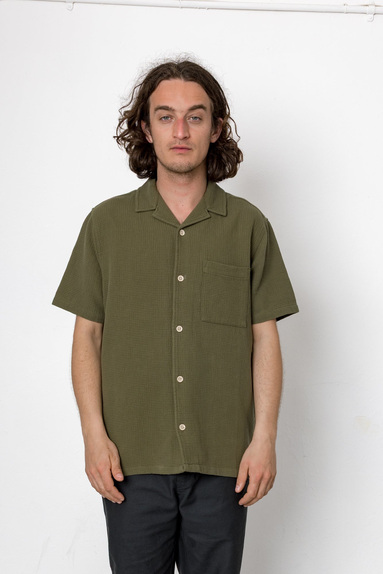 Man wearing an olive green short-sleeve shirt against a white background