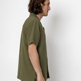 Man wearing an olive green shirt against a white background