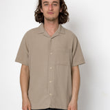 Man wearing a beige short-sleeve shirt against a white background