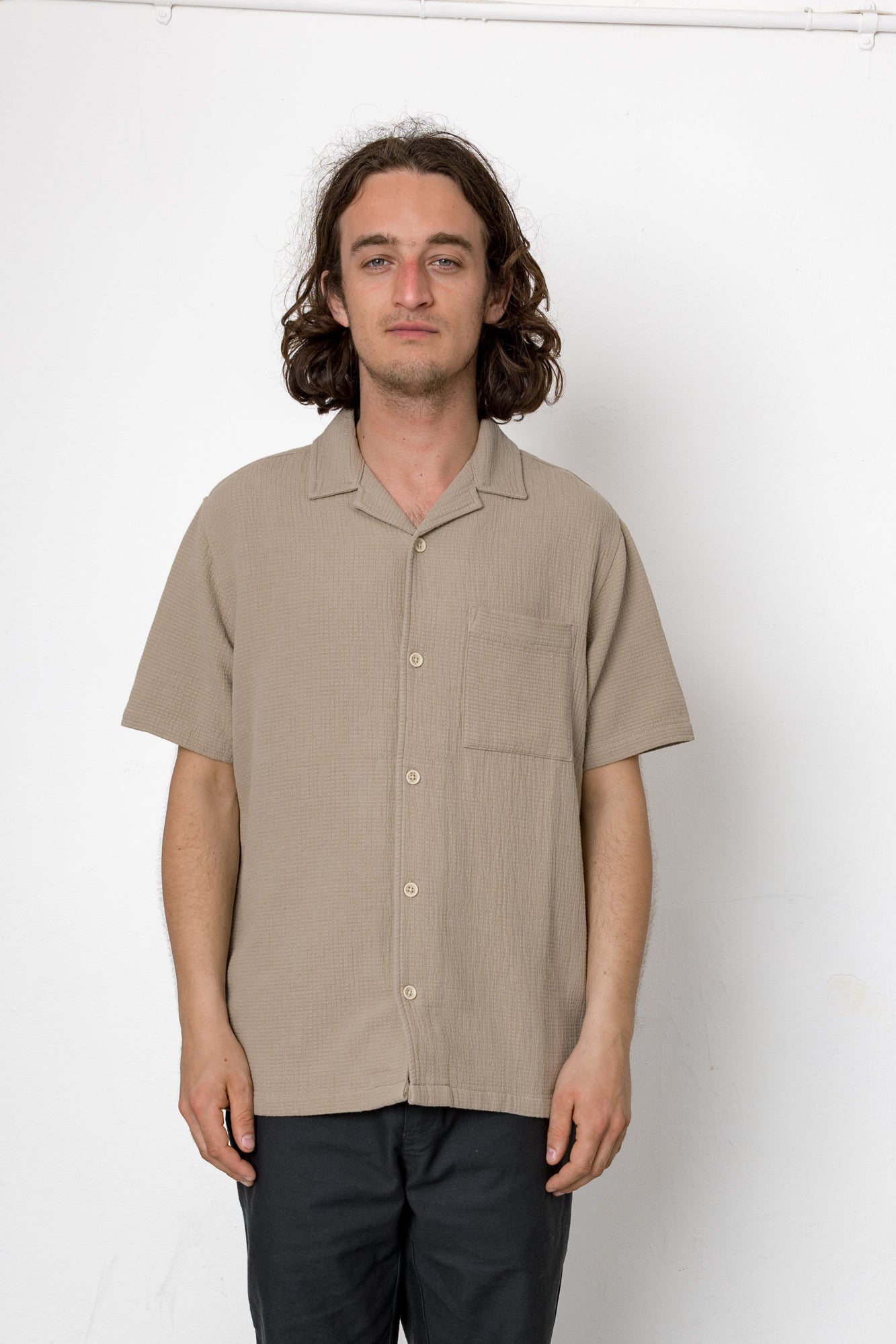 Man wearing a beige short-sleeve shirt against a white background