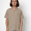 Man wearing a beige short-sleeve shirt against a white background