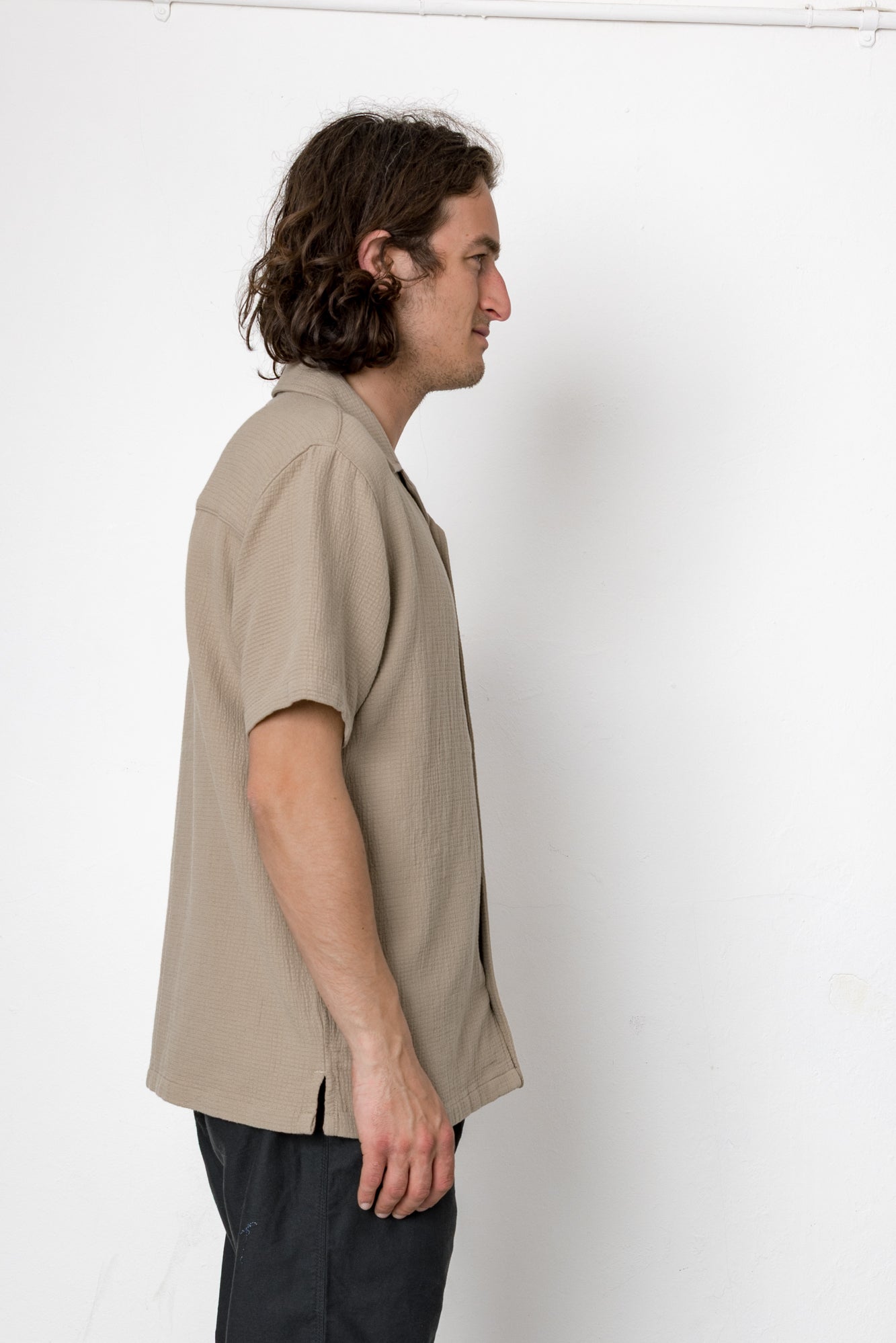 Man wearing a beige short-sleeve shirt against a white background