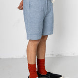 Person wearing blue shorts, black sneakers, and red socks on a white background