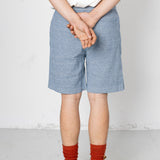 Person wearing blue shorts and red socks with a white background