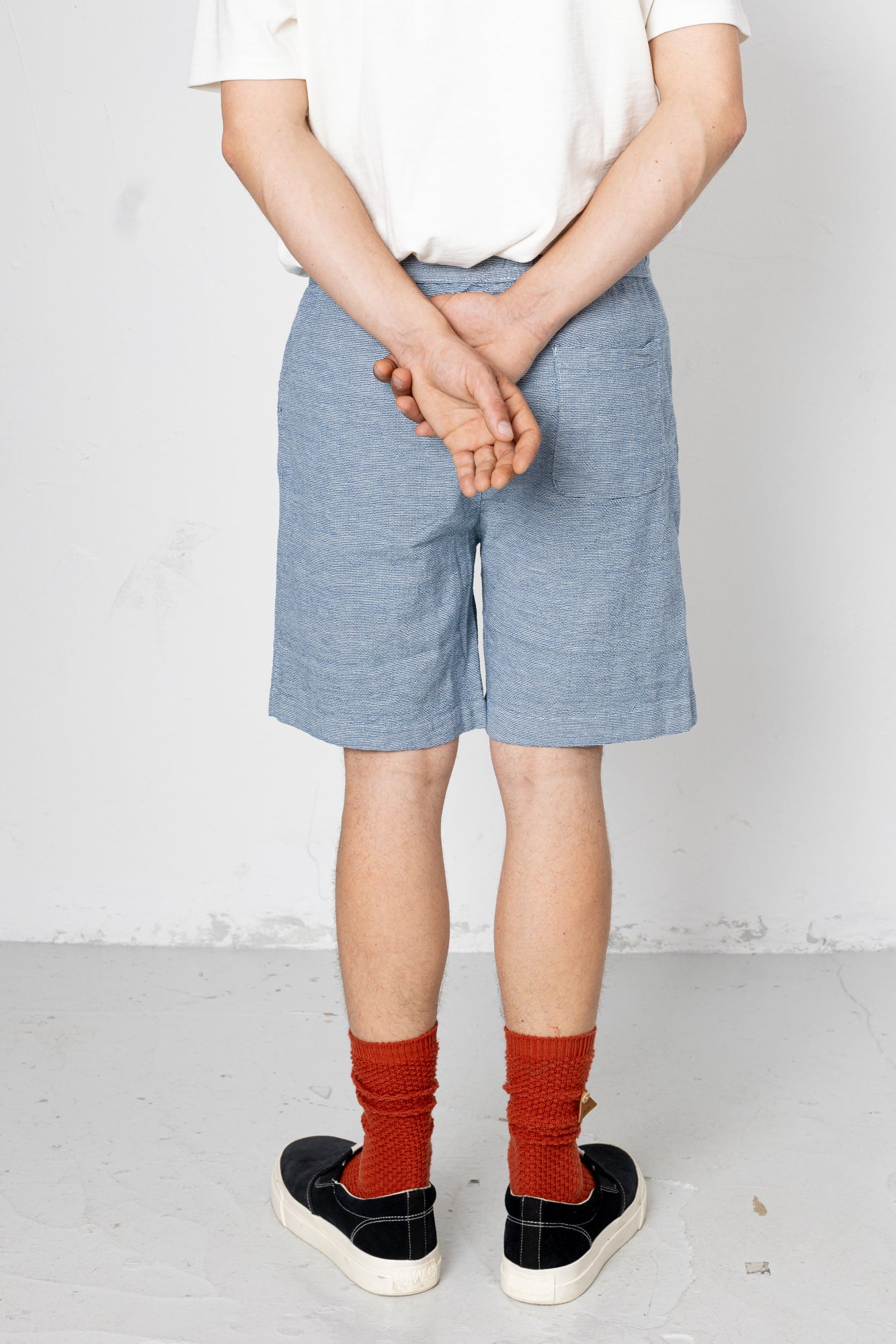 Person wearing blue shorts and red socks with a white background