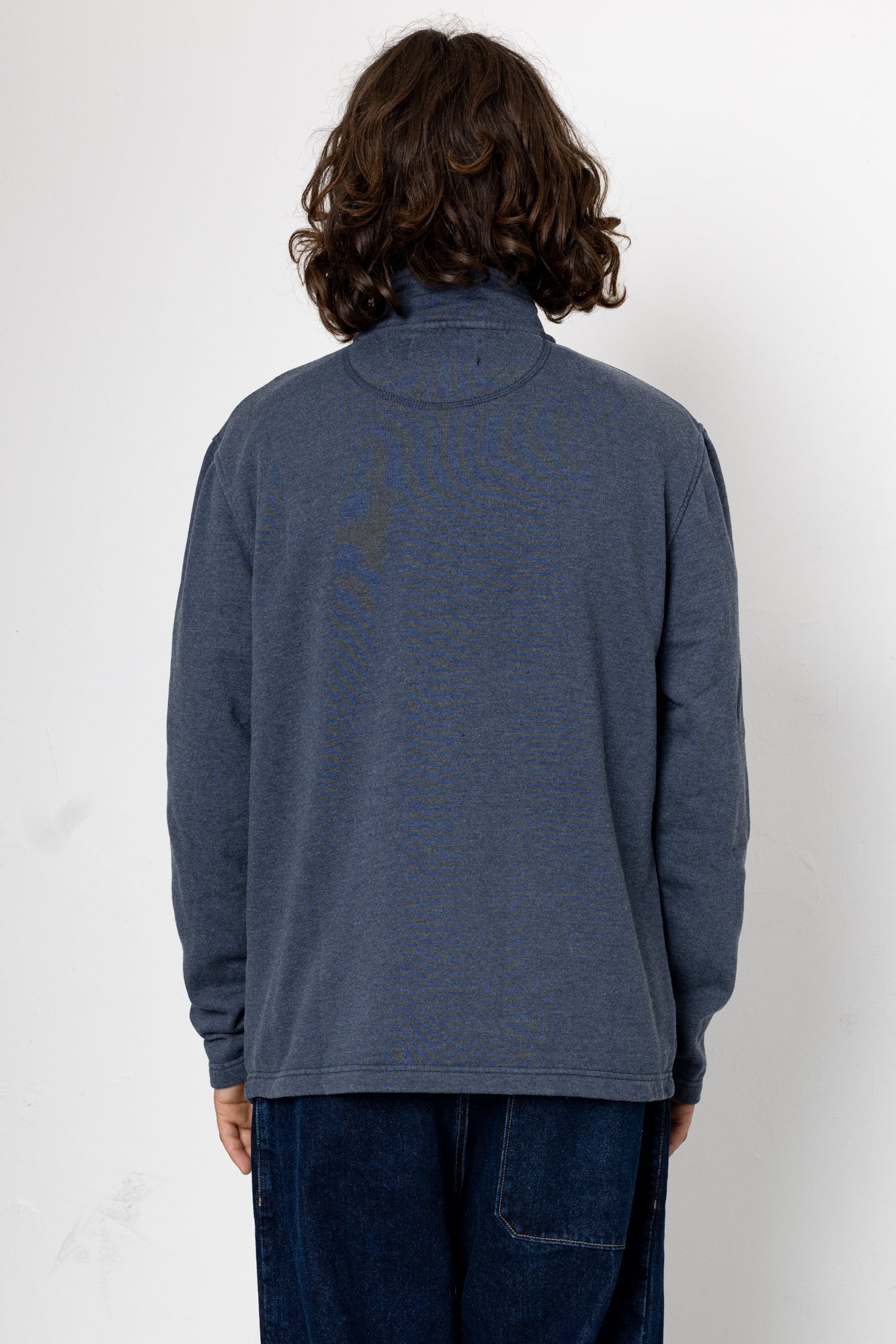 Person wearing a blue sweater against a white background
