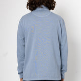 Person wearing a light blue long-sleeve shirt with a pattern on the back against a white background