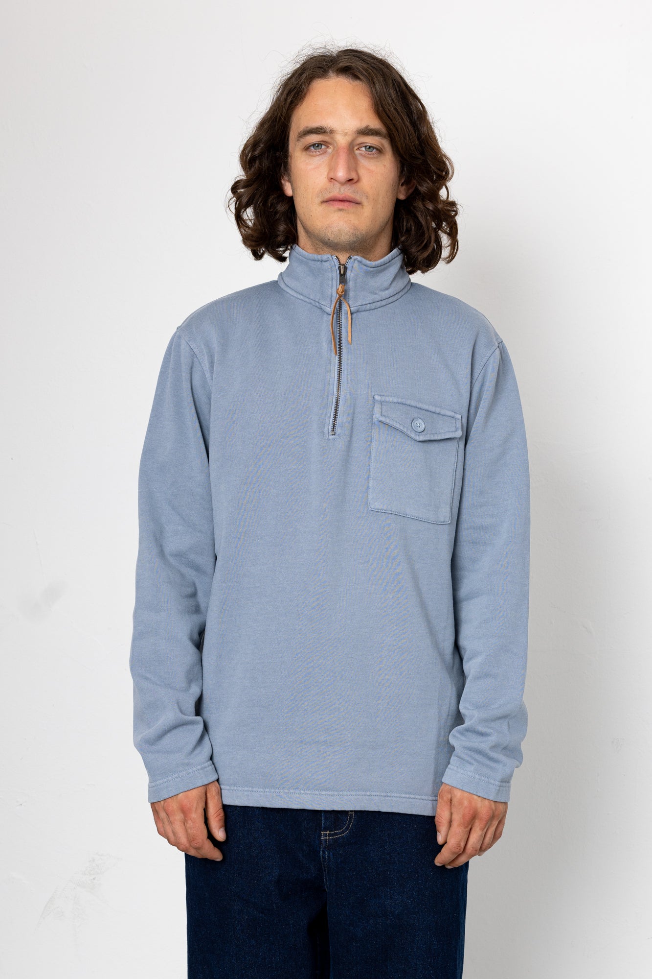 Man wearing a light blue pullover with a pocket on a white background