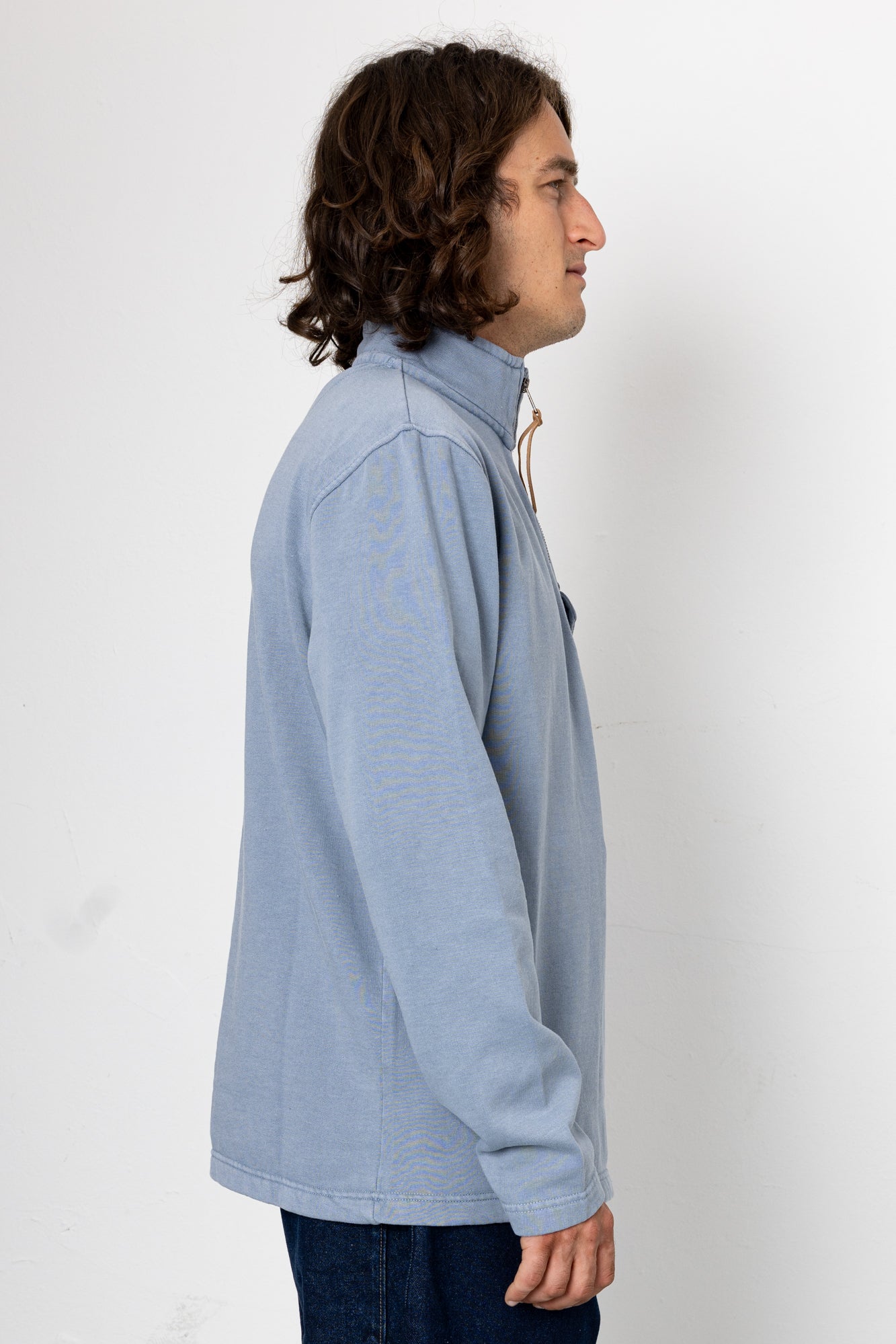 Person wearing a light blue pullover against a white background