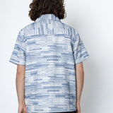 Person wearing a blue patterned shirt against a white background