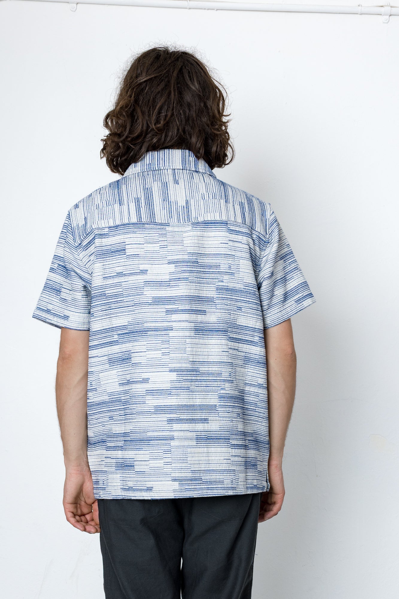 Person wearing a blue patterned shirt against a white background