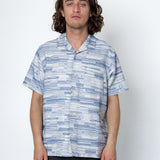 Man wearing a blue and white patterned shirt against a white background