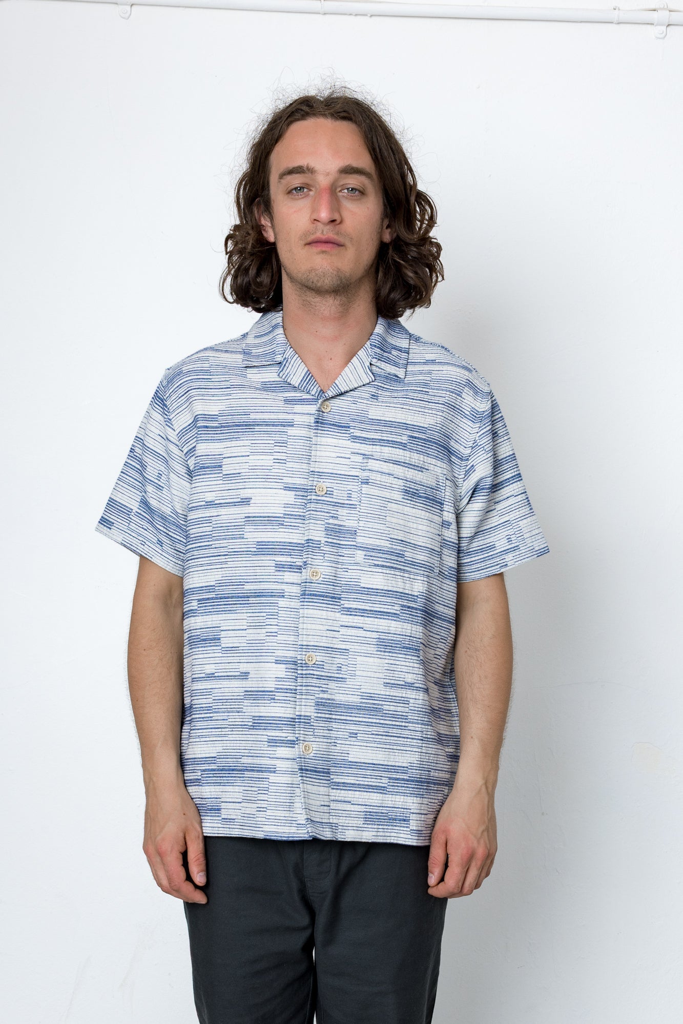 Man wearing a blue and white patterned shirt against a white background