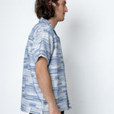 Man wearing a blue and white patterned shirt against a white background