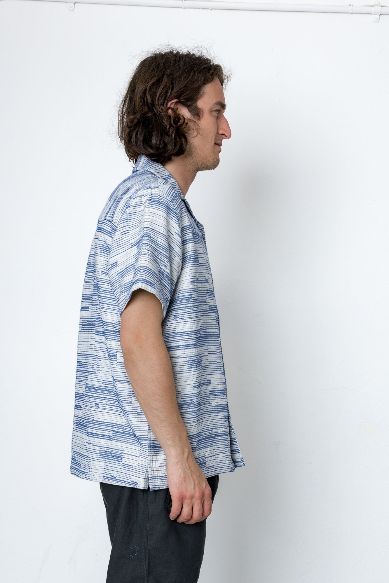 Man wearing a blue and white patterned shirt against a white background