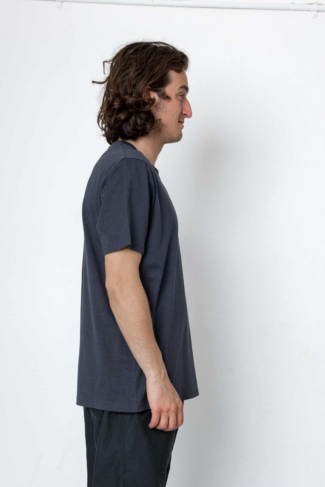 Man wearing a dark gray t-shirt and pants against a white background
