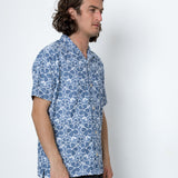 Man wearing a blue patterned shirt against a white background