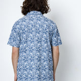 Person wearing a blue floral patterned shirt against a white background