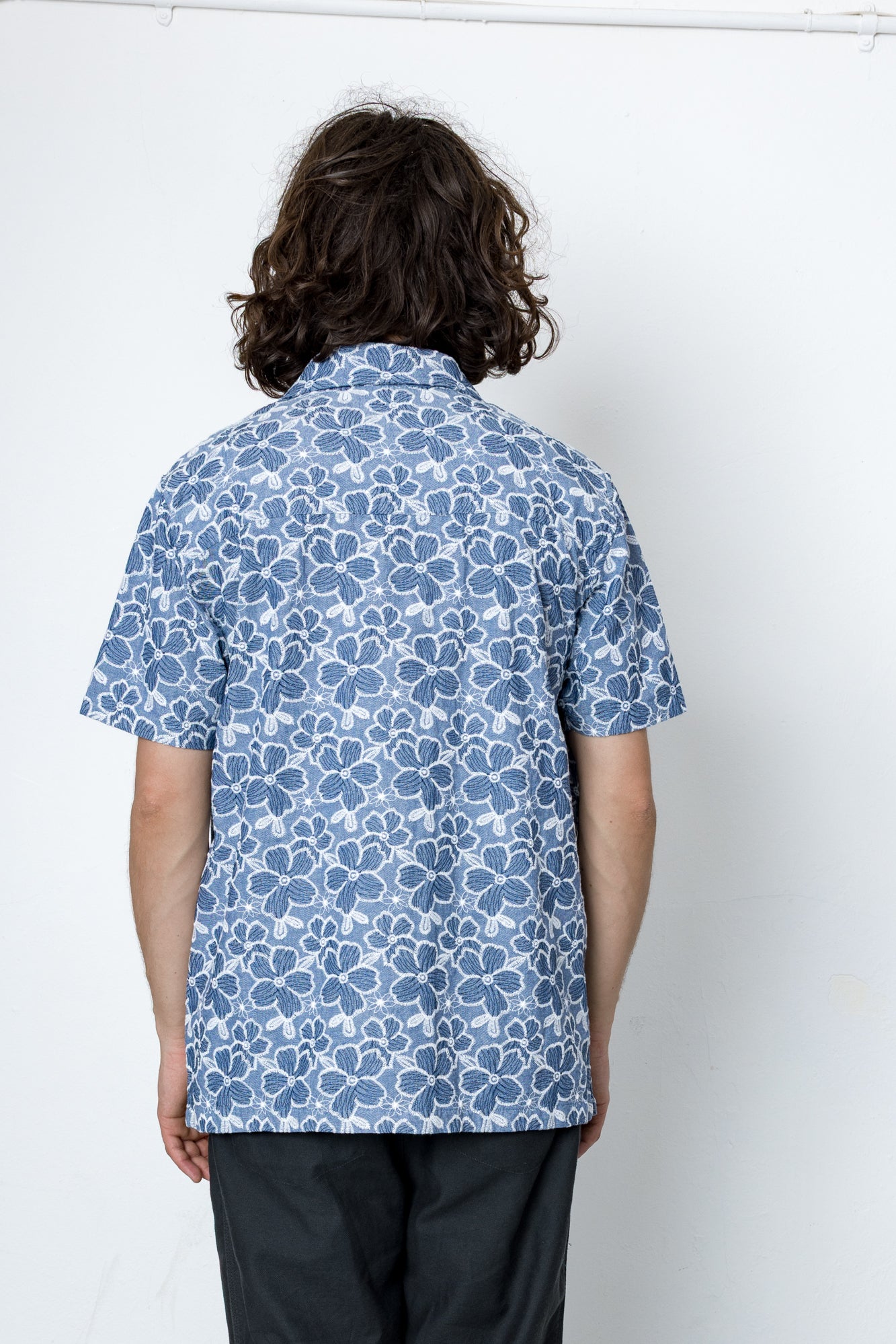Person wearing a blue floral patterned shirt against a white background