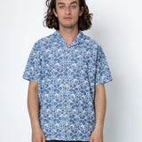 Man wearing a blue patterned shirt against a white background