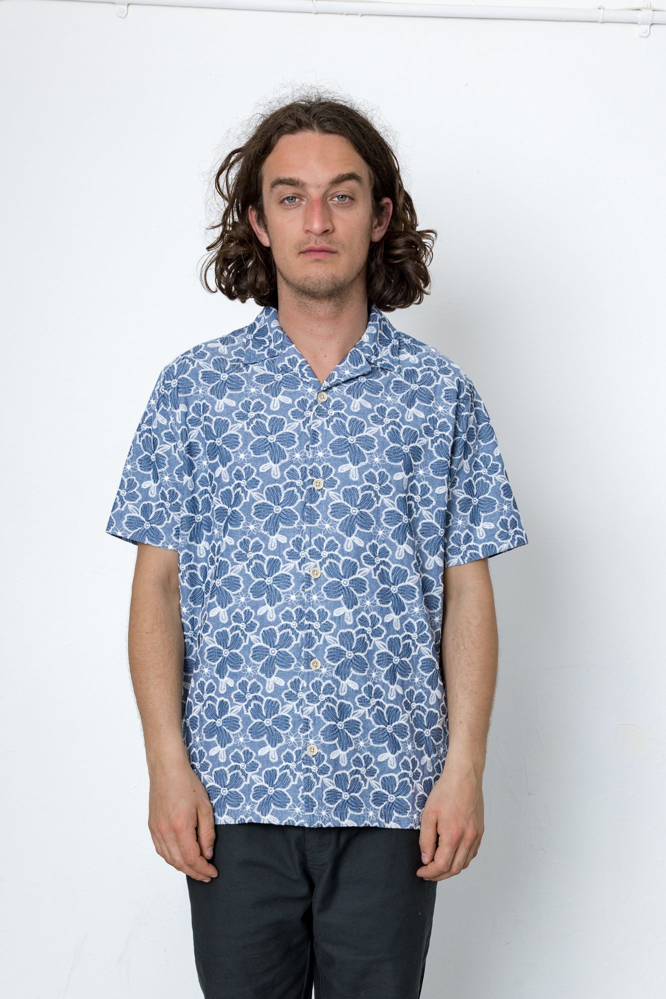 Man wearing a blue patterned shirt against a white background