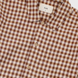 A close-up of a brown and beige gingham checkered button-down shirt by Folk, showing the collar, buttons, and fabric texture.