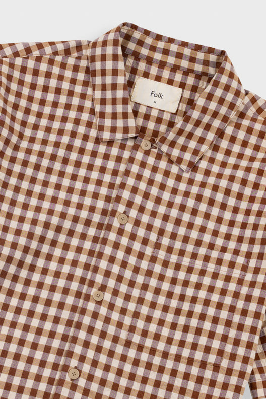 A close-up of a brown and beige gingham checkered button-down shirt by Folk, showing the collar, buttons, and fabric texture.