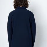 Person wearing a navy blue jacket against a white background