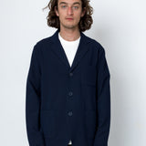 Man wearing a navy blazer over a white shirt on a white background