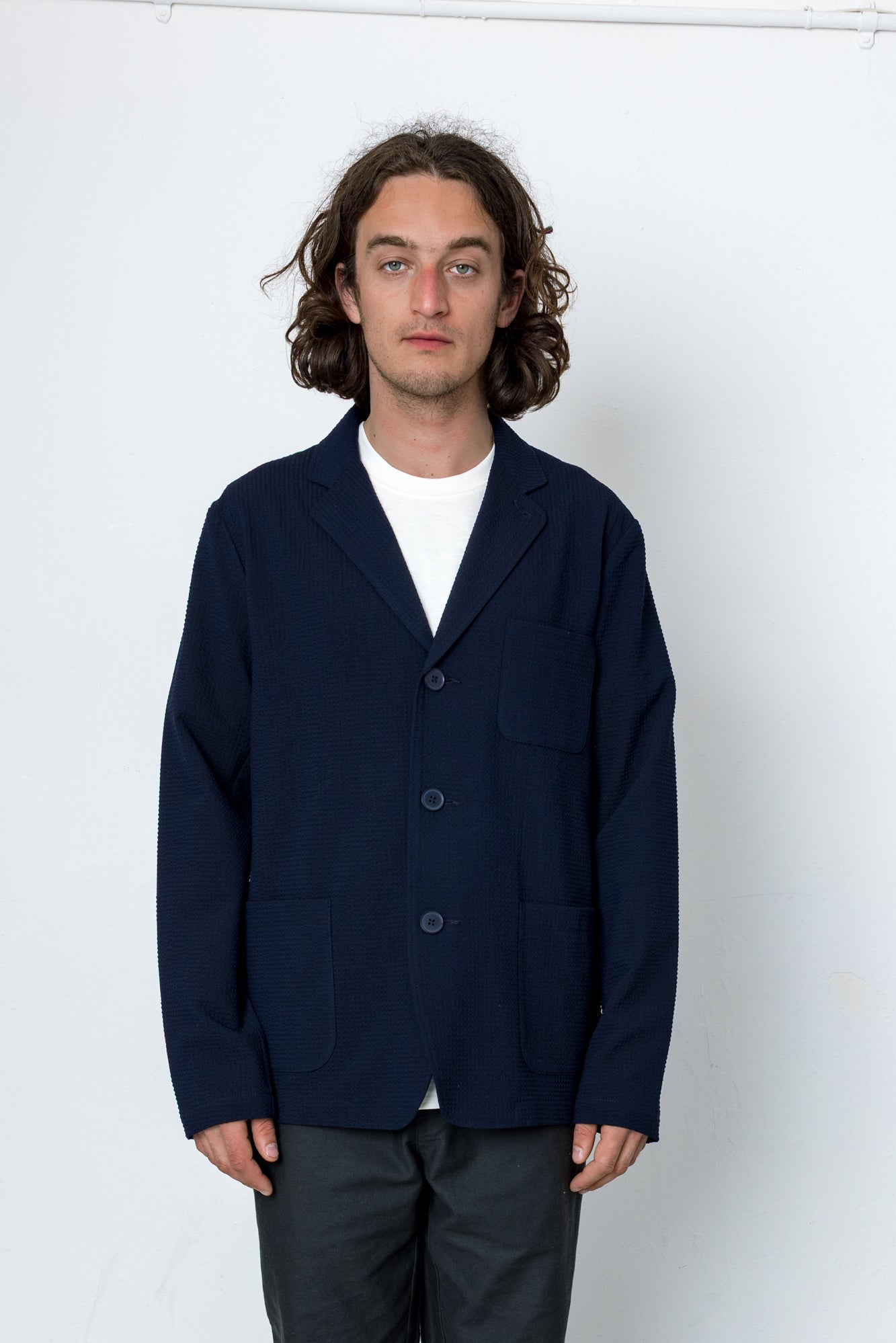 Man wearing a navy blazer over a white shirt on a white background