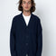 Man wearing a navy blazer over a white shirt on a white background