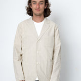 Man wearing beige striped blazer and dark trousers