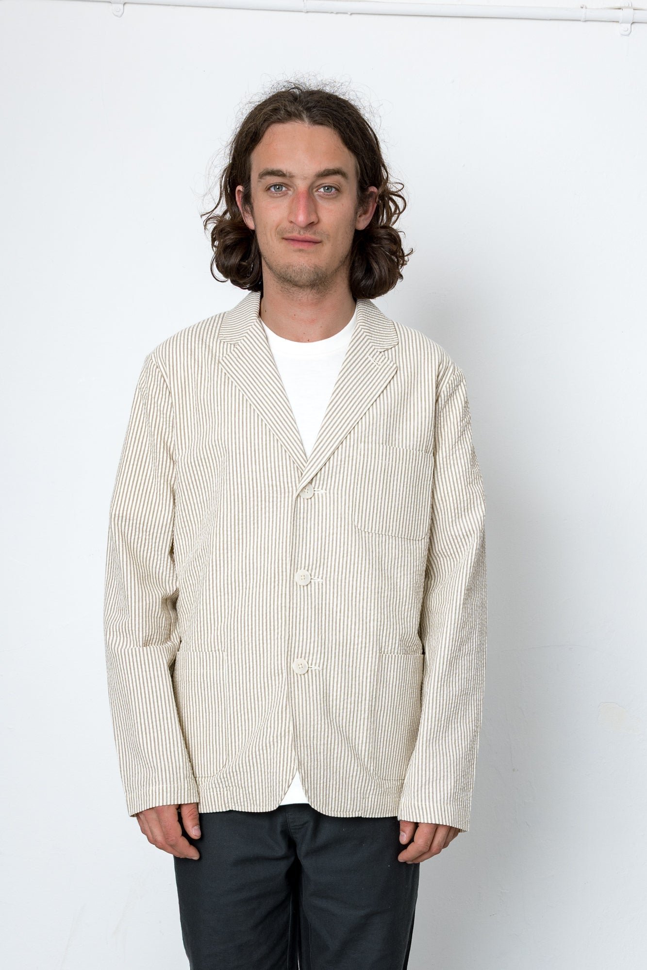 Man wearing beige striped blazer and dark trousers