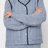Person wearing a blue and white striped vest over a jumper with a plain background