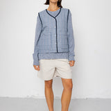 Woman wearing a blue striped vest and white shorts against a white background