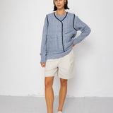 Woman wearing a blue striped vest and white shorts against a white background