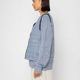 Woman wearing a blue striped vest and white shorts against a white background