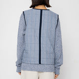 Person wearing a blue and white striped vest with a plain background
