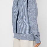 Woman wearing a blue striped vest and white shorts against a white background