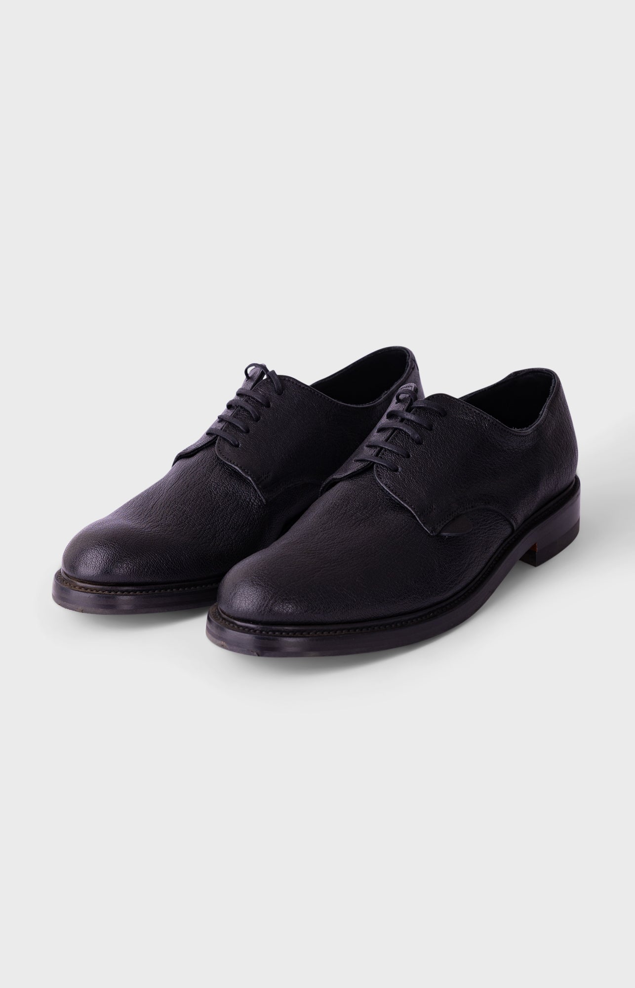 Black sneakers with white soles on a light gray background
