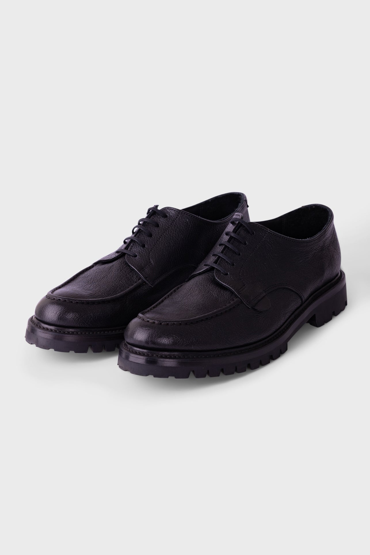 Black sneakers with white accents on a light gray background