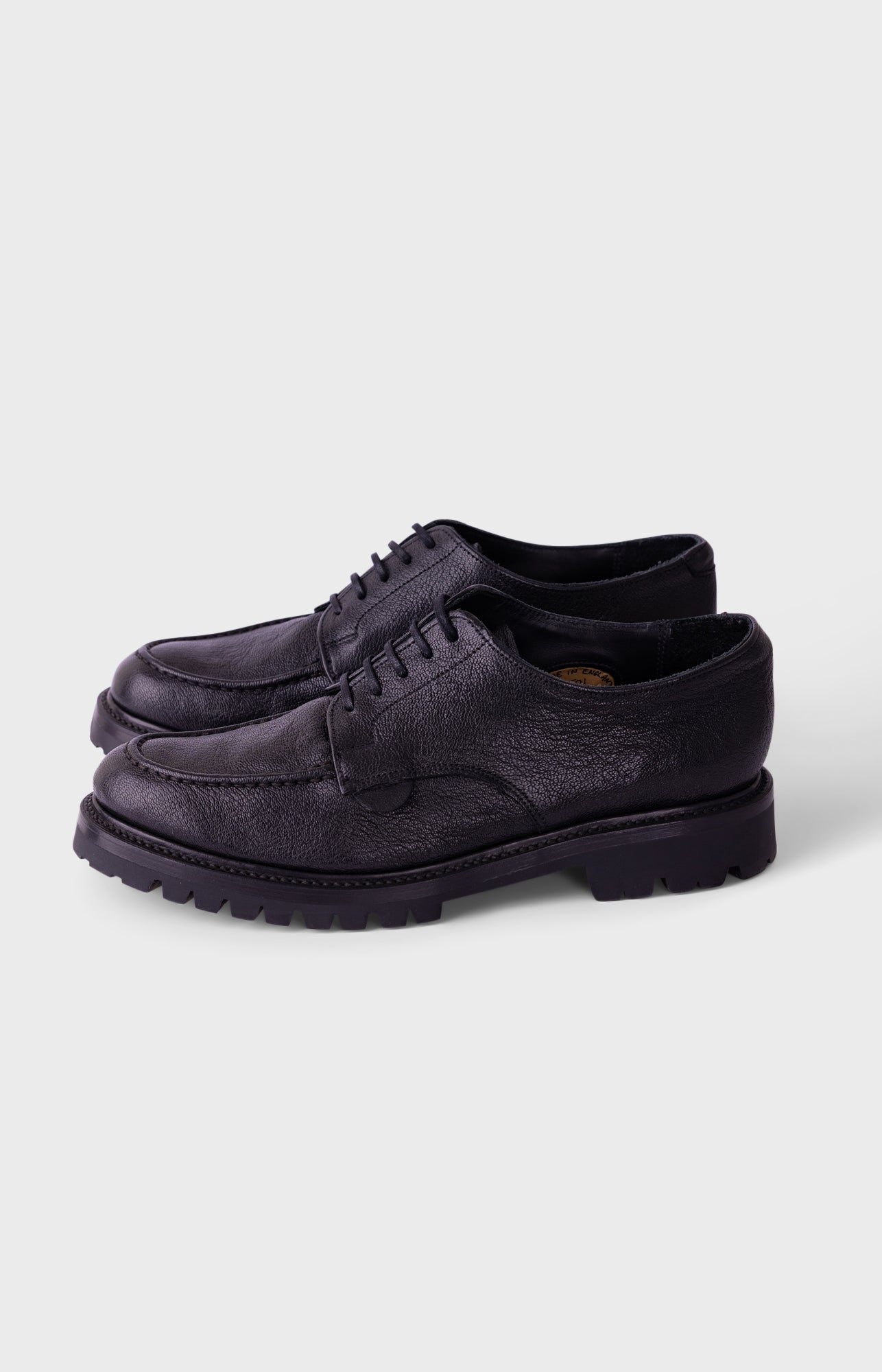 A pair of dark navy blue leather lace-up shoes with thick lug soles, displayed on a light gray background.