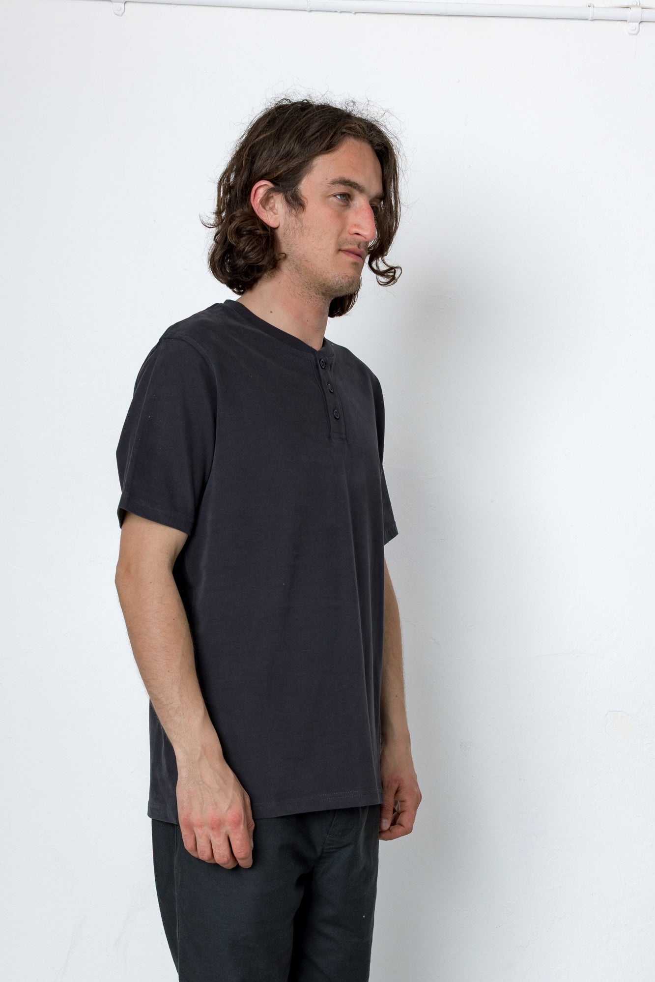 Man wearing a dark gray t-shirt and pants against a white background