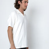Man wearing a white polo shirt against a white background
